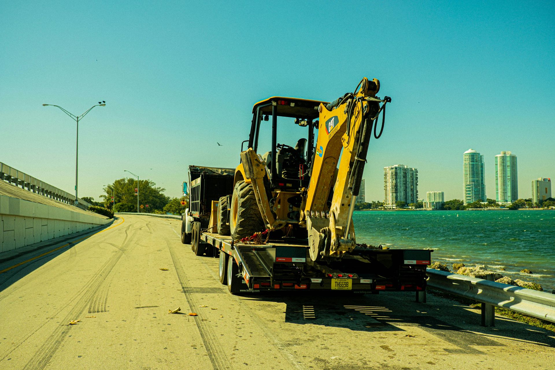 yellow and black heavy equipment on gray concrete road near body of water during daytime